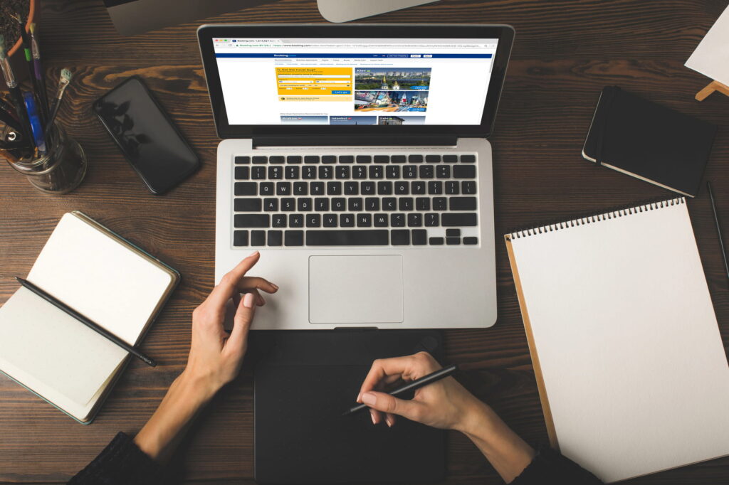 Person using a laptop and graphic tablet at a desk with notebooks, illustrating web design and development services.